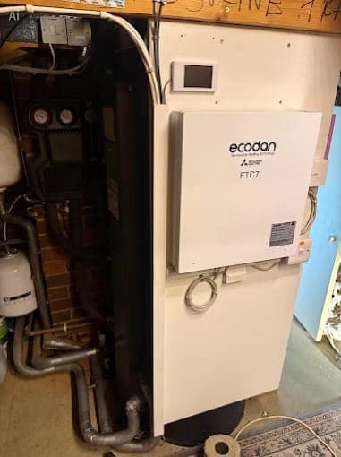 A heat pump controller and pipework inside a utility cupboard