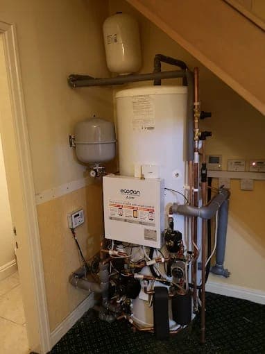 A heat pump cylinder and controller fitted in an understairs cupboard