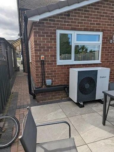 A Vaillant heat pump on a patio beside a single storey extension