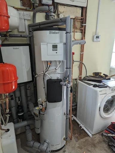 A Vaillant heat pump cylinder and controls in a utility room beside a washing machine
