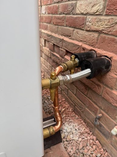 Through the wall Pipework connected to a wall, featuring brass fittings and copper tubing.