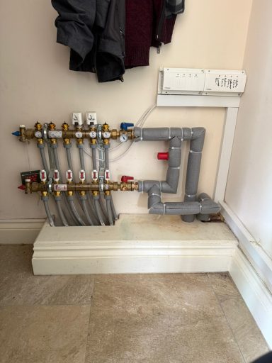 Underfloor Manifold Heating system manifold with pipes and valves mounted on a wall.